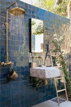 a blue tiled bathroom with a shower head, sink and ladder in the shower area