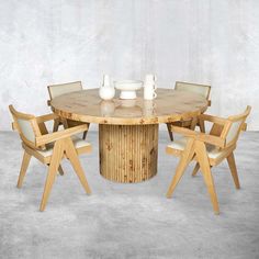 a round wooden table with four chairs around it and two vases on the table