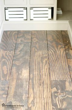 a wood floor with white cabinets in the background