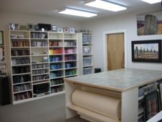 a room with several bookshelves and pictures on the wall, including one desk