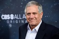 an older man in a black suit and white shirt smiles at the camera while standing in front of a blue background