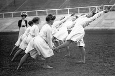 several women in white dresses are doing tricks on the field with their hands behind their backs