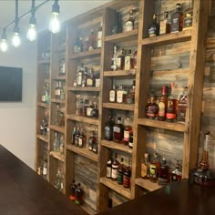 a wooden shelf filled with lots of bottles on top of a wall next to a bar