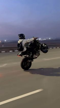 a man riding on the back of a motorcycle down a street next to an airport