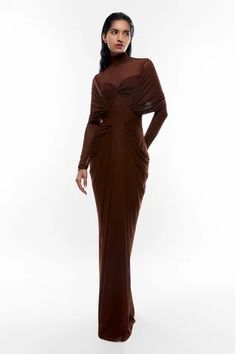 Chocolate brown fitted gown with draping on the bodice, sheer panel at the neckline and cowl drapes below the waist on the sides.
Components: 1
Neckline: High Neck
Sleeve Type: Long
Fabric: Net and Malai Lycra
Color: Brown
Other Details: 
Pleats in front
Keyhole cutout at the back
Closure: Back zip
Occasion: Party - Aza Fashions Draped Gown, Fitted Gowns, Draped Bodice, Drape Gowns, Gown For Women, High Neck Designs, Gowns Online, Draped Dress, Long Sleeve Maxi