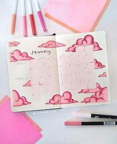 an open planner with pink clouds on it