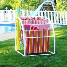 a rack with towels and umbrellas in the grass next to a pool