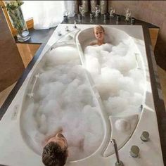 two people are in the bathtub with soapy water and bubbles on the floor