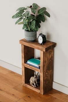 a wooden shelf with books and a clock on it next to a potted plant