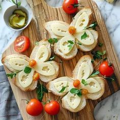 several pieces of bread with cheese and cherry tomatoes on them sitting on a cutting board