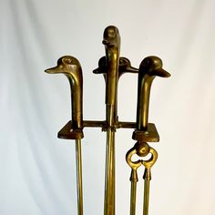 three golden metal birds are standing next to each other on a white tablecloth background