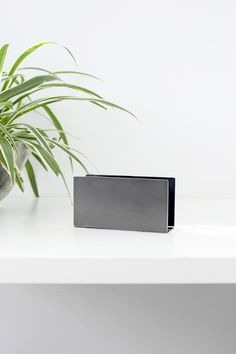 a plant sitting on top of a white table next to a black box with silver foil