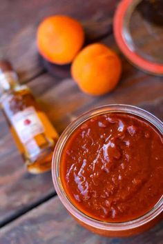 a jar filled with sauce next to two oranges