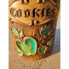 a close up of a vase on the ground with words and leaves painted on it