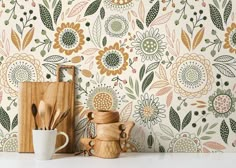 an assortment of kitchen utensils and wooden spoons in front of a floral wallpaper