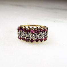 This is a vintage 10K yellow gold ladies gemstone cluster ring.  It is set with 14 round 2.2mm rubies (.56tcw) and 7 round 1mm diamonds (.03tcw).  The band is sized at an 8.  The ring face measures 5/8" wide x 5/16" long.  Total weight is 2.9 grams.   This is a vintage, previously owned ring.  Therefore, light wear can be expected.  There is no visible damage. Ruby And Diamond Cluster Ring, Anniversary Ruby Cluster Ring With Multi-stone, Anniversary Cluster Ruby Ring With Multi-stones, Anniversary Multi-stone Cluster Ruby Ring, Vintage Diamond Cluster Ring With Accent Stones, Vintage Multi-stone Diamond Ruby Ring, Vintage Ruby Cluster Ring With Multi-stones, Vintage Multi-stone Ruby Ring With Diamonds, Vintage Multi-stone Ruby Cluster Ring