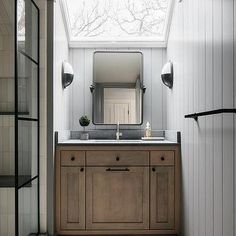 a bathroom with a skylight above the sink and mirror on the wall next to it