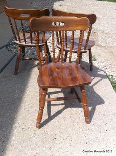 three wooden chairs sitting next to each other on the sidewalk in front of a house