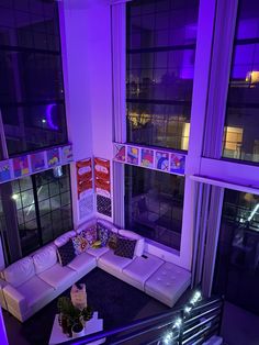 a living room filled with white furniture and purple lighting on the windows sill above it