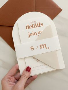 a person is holding an envelope with the letter s and m on it in front of some brown envelopes