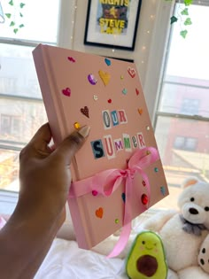 someone is holding up a pink book with the word summer written on it next to stuffed animals