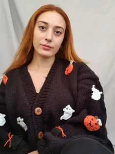 a woman with red hair wearing a black cardigan and orange cats on the sleeves