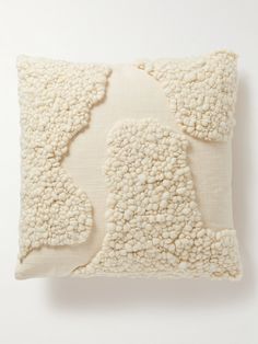 a white pillow with an abstract design on the front and back, sitting on a white surface