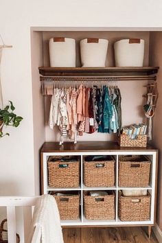 an organized closet with baskets and clothes hanging on the wall, next to a white bench