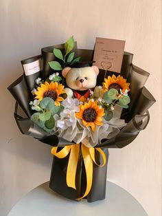 a bouquet of sunflowers with a teddy bear in the center and a note attached to it