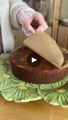 a person cutting into a chocolate cake on top of a green plate