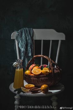 a basket filled with oranges sitting on top of a table next to a bottle of juice