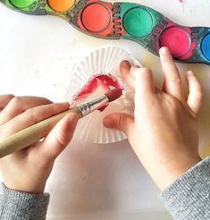 a person is painting on paper with paintbrushes