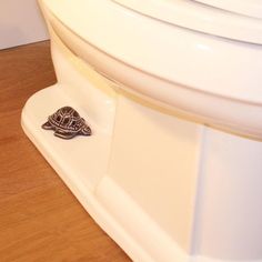 a small turtle is sitting on the edge of a toilet bowl lid and it's head sticking out