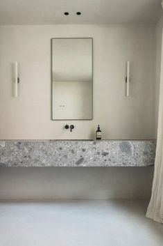 an empty bathroom with marble counter tops and white walls, along with two mirrors on the wall