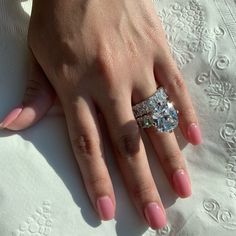 a woman's hand with pink manicured nails and a ring on her finger