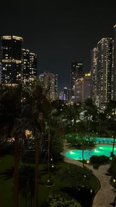 the city skyline is lit up at night with lights reflecting in the pool and palm trees