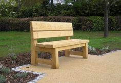 a wooden bench sitting in the middle of a park next to some bushes and trees