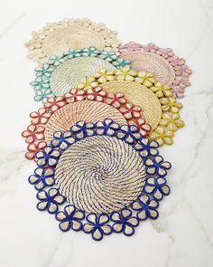 six woven placemats in different colors on a marble surface