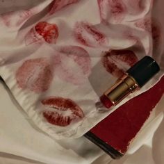 a lipstick on top of a white cloth next to a red bag with an apple print