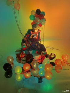 a clown sitting on top of a box filled with balloons