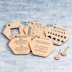 four wooden tags with numbers on them sitting on a blue cloth next to some earrings