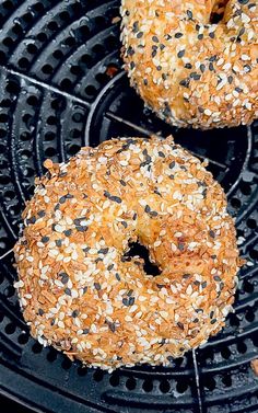 two bagels sitting on top of a grill with sesame seed sprinkles