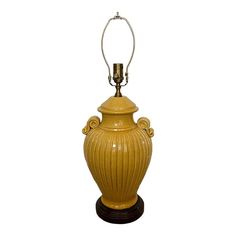 a yellow urn with a light on top of it and a metal pole in the middle