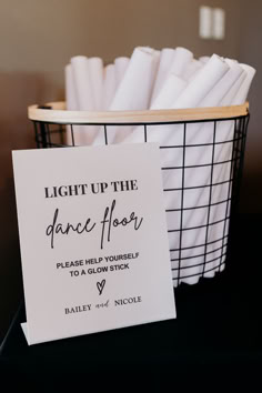 a basket with napkins in it and a sign that says light up the dance floor