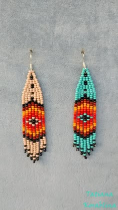 two colorful beaded earrings hanging from hooks on a gray surface with a blue background