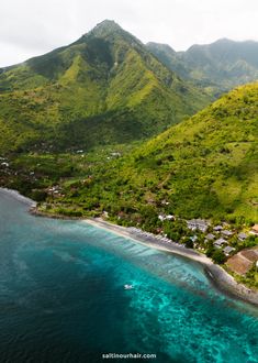 an aerial view of the ocean and mountains with houses on it's sides, surrounded by lush green vegetation