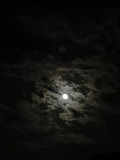 the full moon shines brightly in the dark night sky with clouds and trees around it