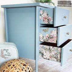 a blue cabinet with flowers painted on it and a wicker basket next to it