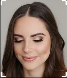 a woman with long brown hair and black eyeliners smiles while wearing a white dress