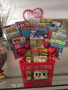 a red basket filled with lots of cards on top of a glass table next to a vase